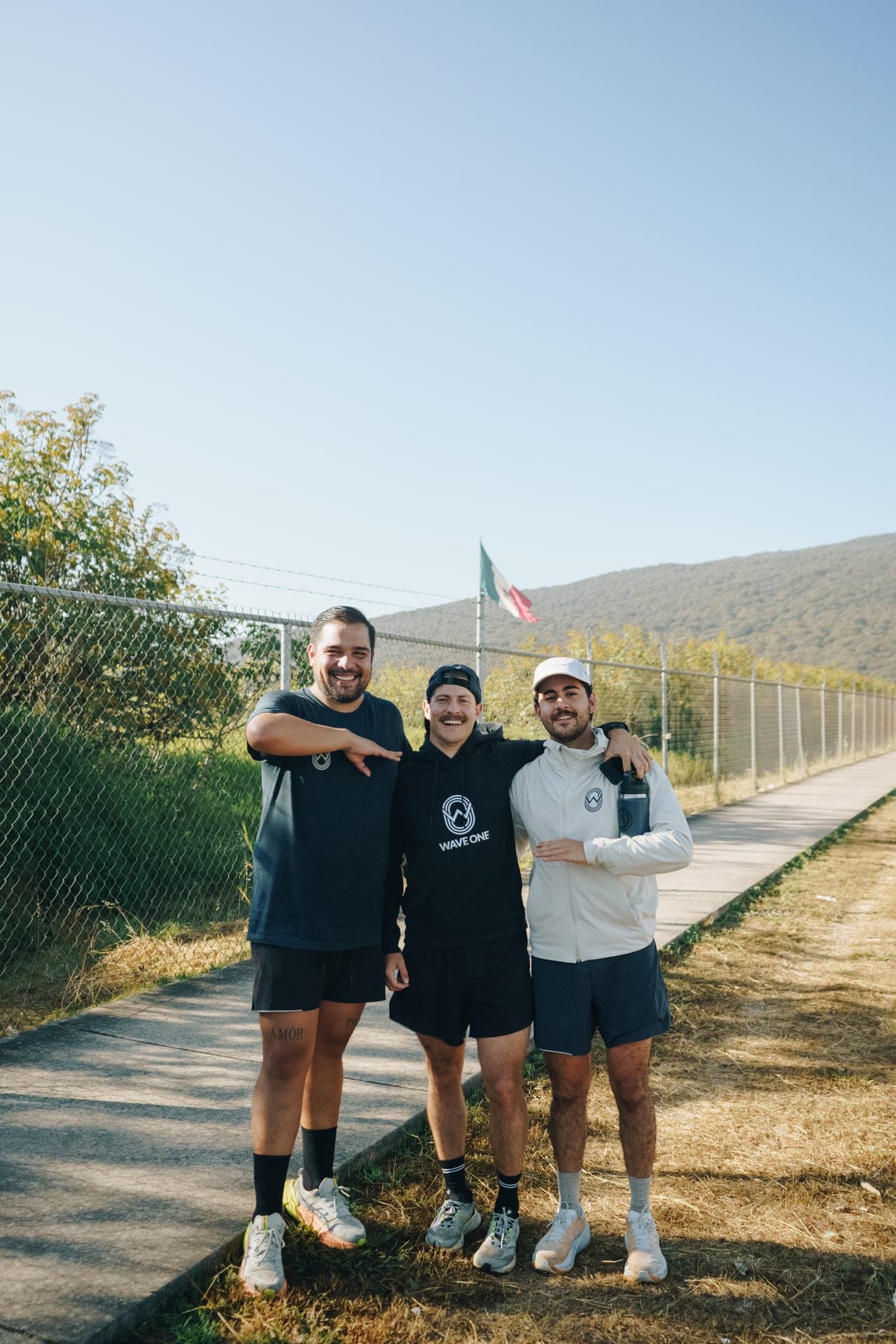 Three Wave One members in club singlets on a country road